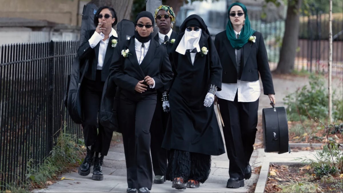 (L-R) Sarah Kameela Impey as Saira, Anjana Vasan as Amina Hussain, Faith Omole as Bisma, Lucie Shorthouse as Momtaz, Juliette Motamed as Ayesha walk down the street wearing black suits in 'We Are Lady Parts'.