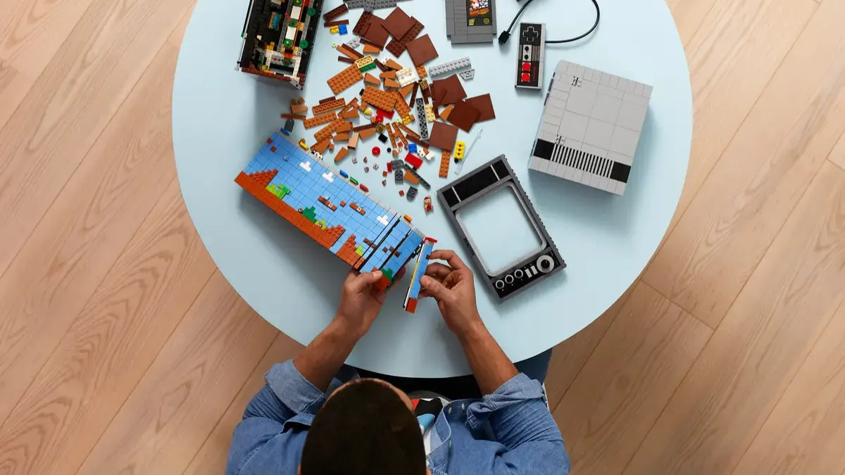 A shot from above showing someone building a LEGO set on a round white table