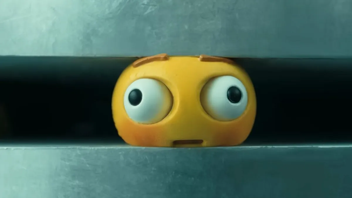 A little yellow ball with eyes and a mouth is crushed in a machine