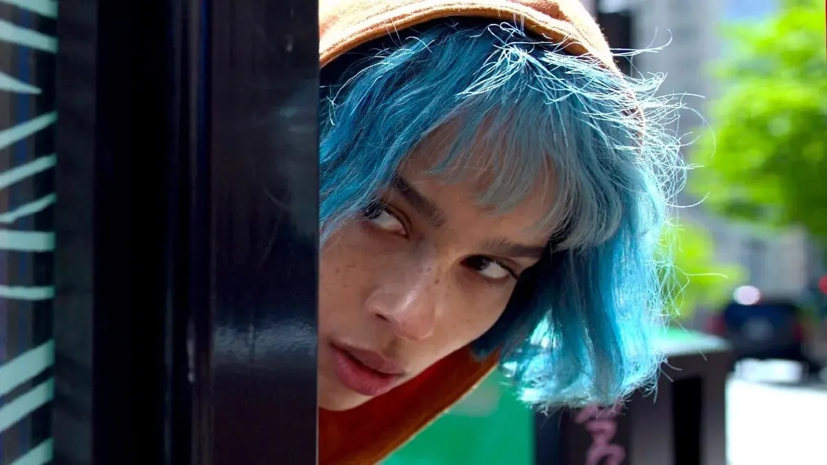 A blue haired woman peers out from a corner in "Kimi"