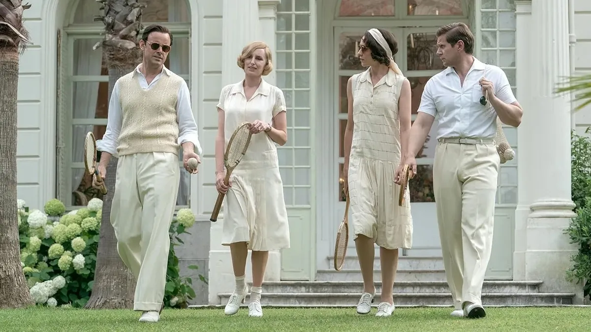 The cast of Downton Abbey walk across the grass wearing tennis outfits.