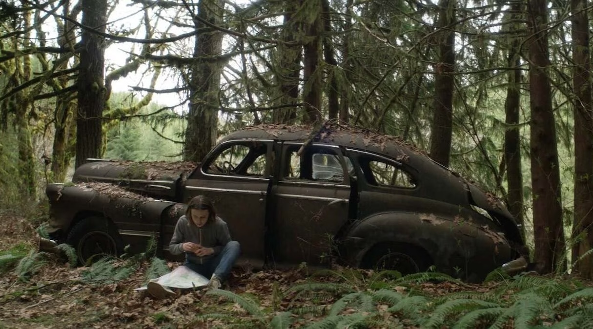 Jessica sits by an abandoned car in the woods in 'New Life.'