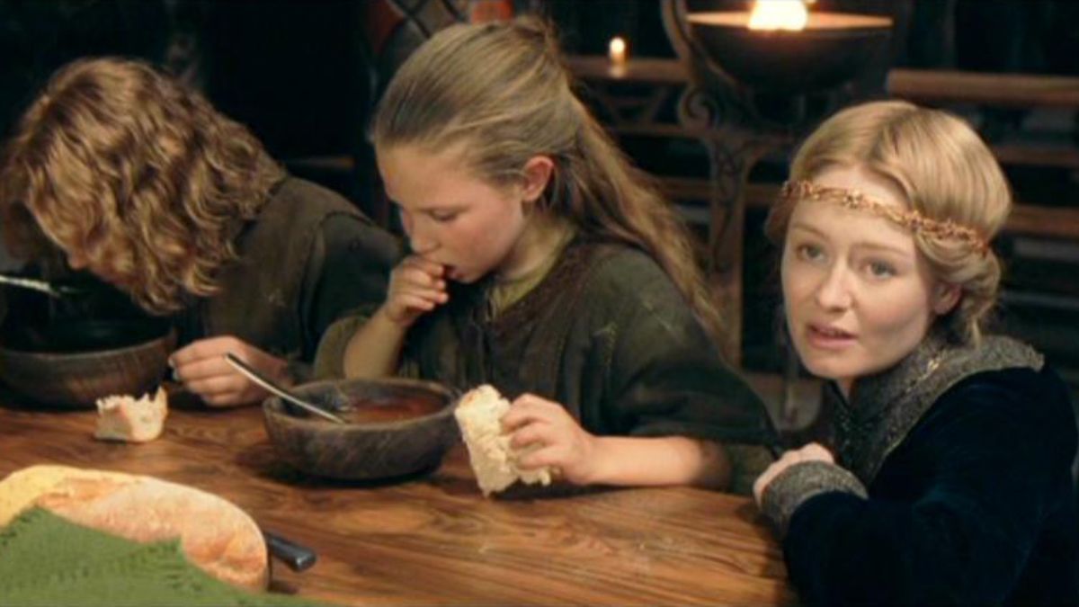 a little boy and girl eat food while an older woman sits next to them