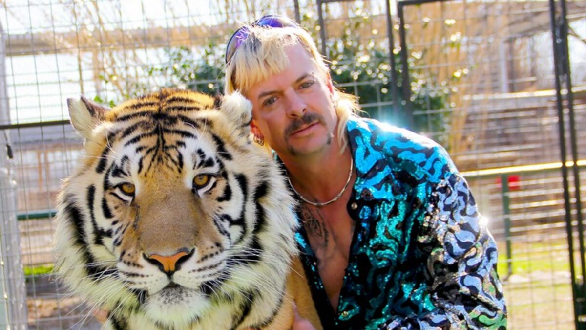 Joe Exotic poses for a photo with three tigers in "Tiger King" (Netflix)