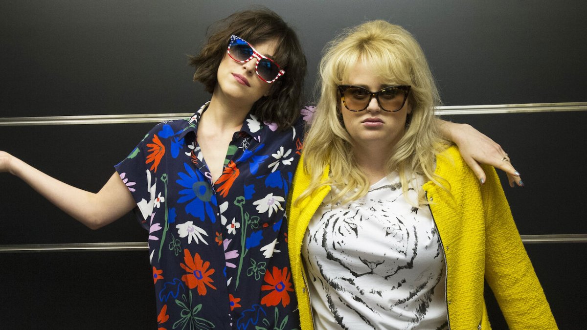 L-R: Alice Kepley (Dakota Johnson) and Robin (Rebel Wilson) wearing glasses and sporting disheveled hair