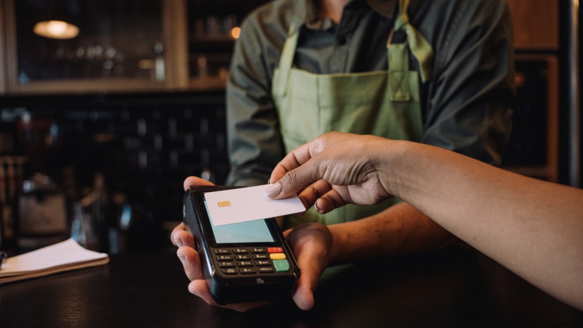A woman uses her credit card to pay at a cafe