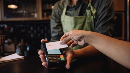 A woman uses her credit card to pay at a cafe