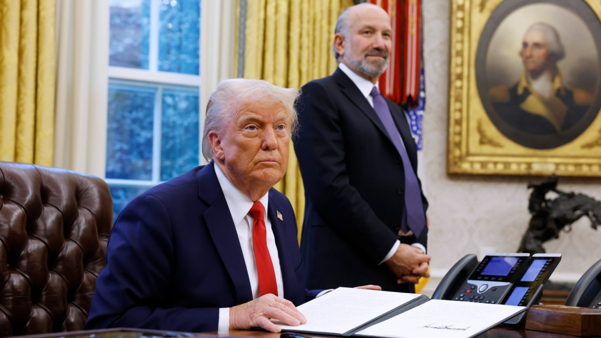 Donald Trump speaks as Commerce Secretary Howard Lutnick looks on