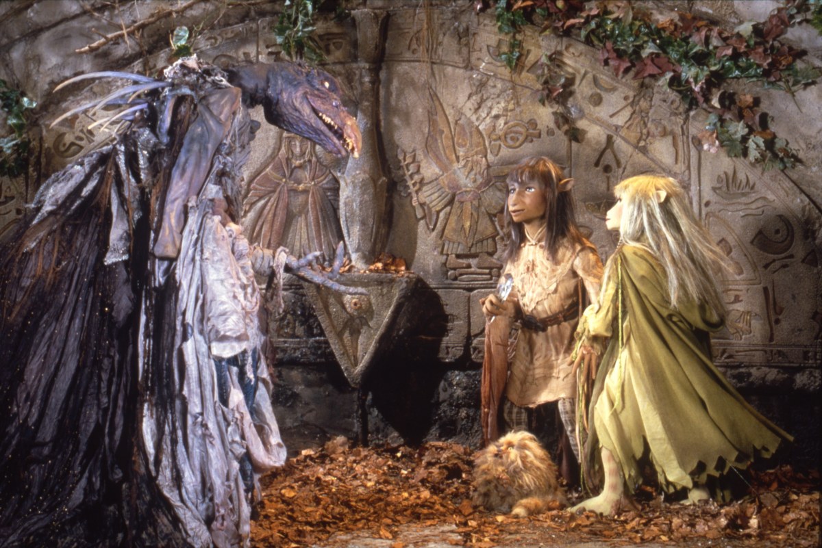 A still featuring the characters of The Dark Crystal (1982) talking to each other in a cave