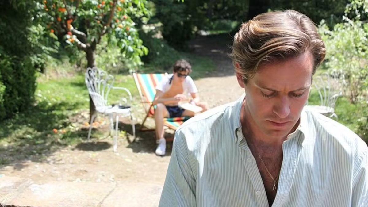 armie hammer looking down with timothee chalamet on a chair