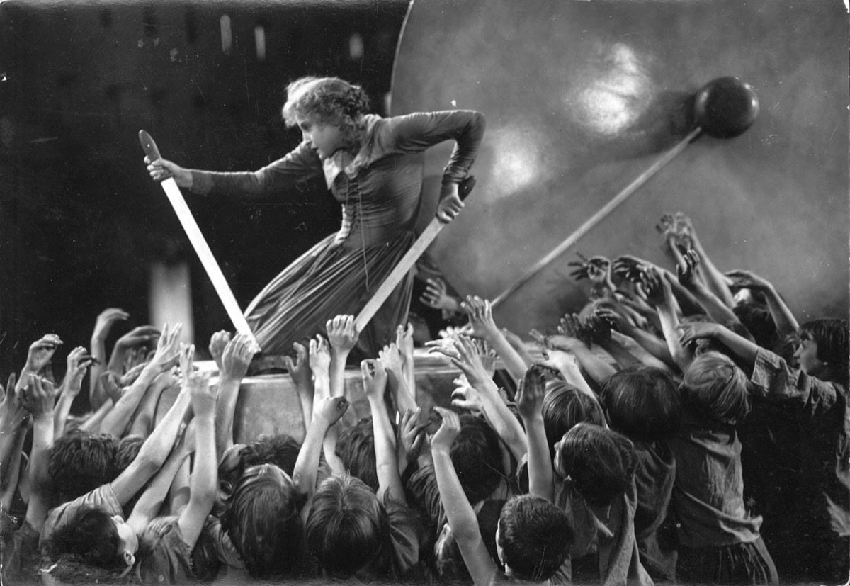 A woman works a machine above a sea of hands in "Metropolis" 