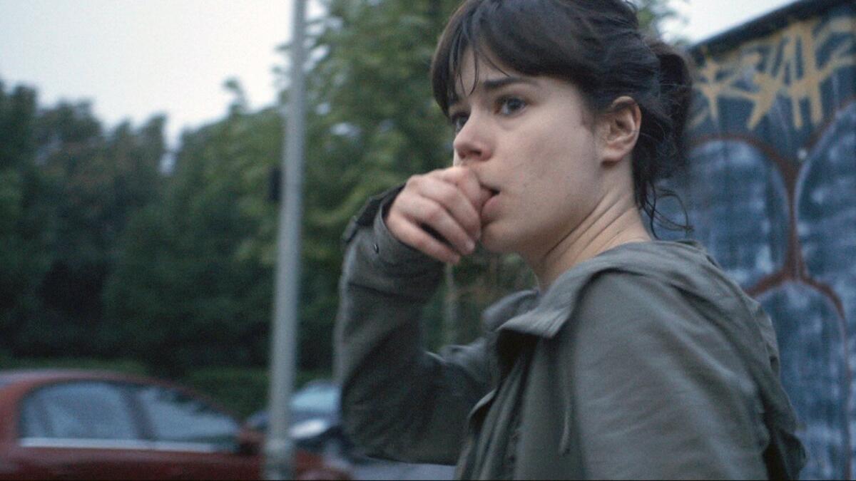 A woman nervously bites her fingernails on a street in "Victoria" 