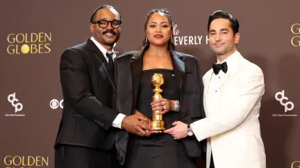 three people standing with an award