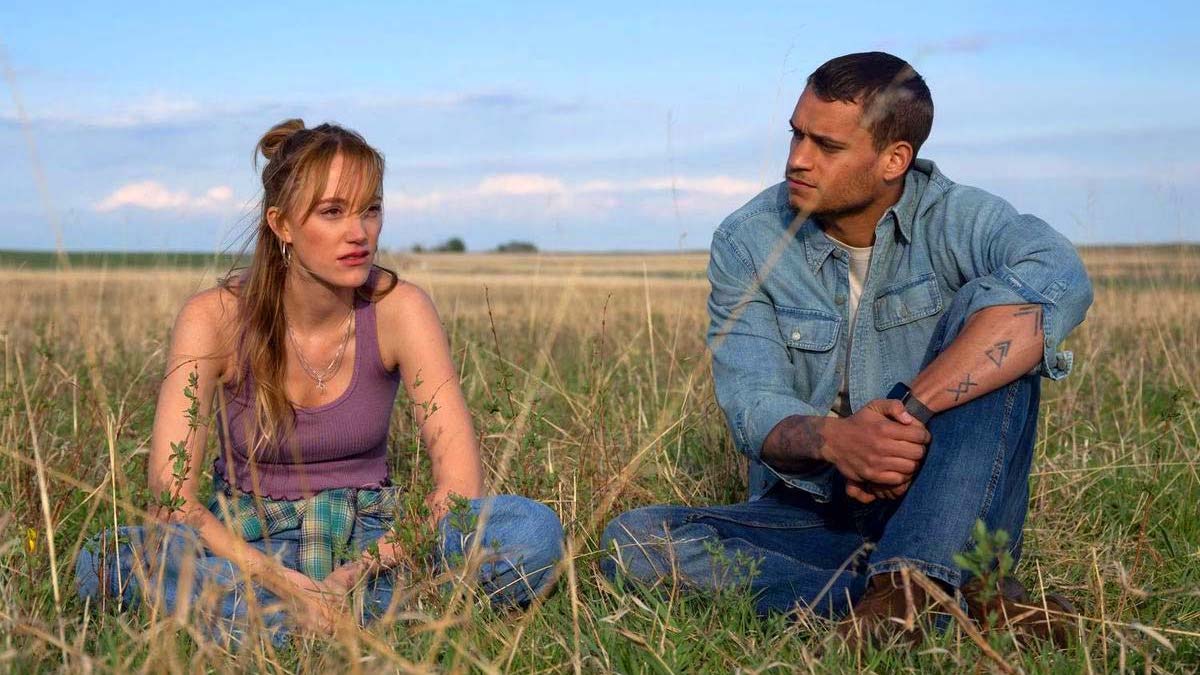 Maika Monroe sits on the grass with Tyriq Withers in Reminders of Him 