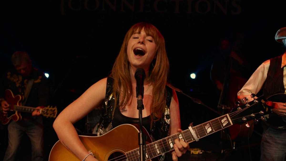 Jessie Buckley playing guitar and singing in Wild Rose