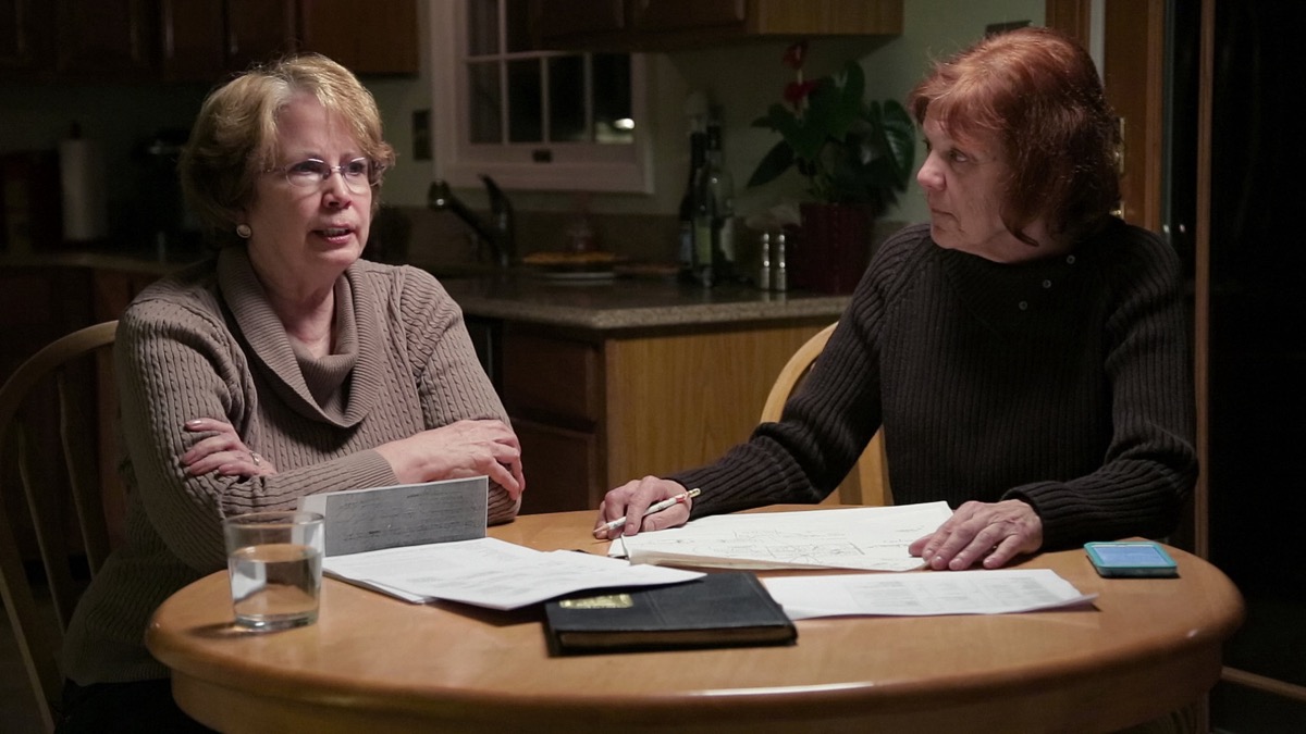 Two women sit at a table and talk in the documentary "The Keepers" 