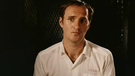 A man with a pained look on his face sits for an interview in 