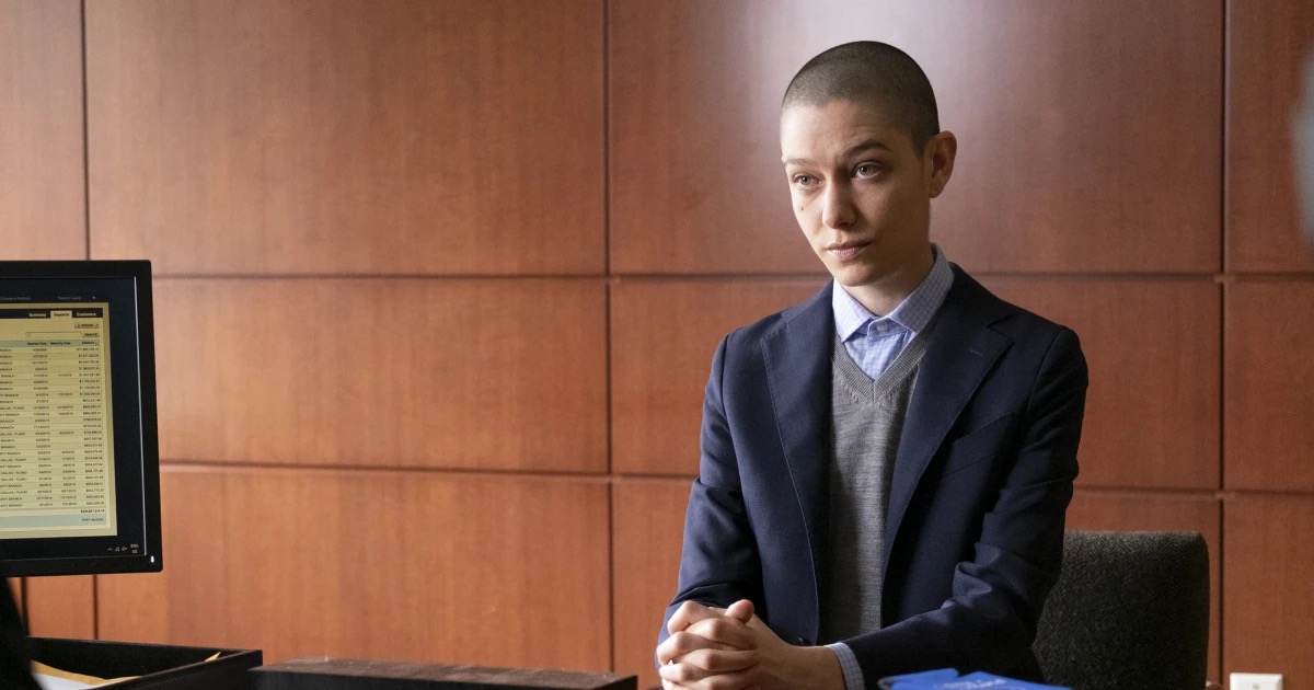 A person in a business suit sits with hands folded in "Billions" 