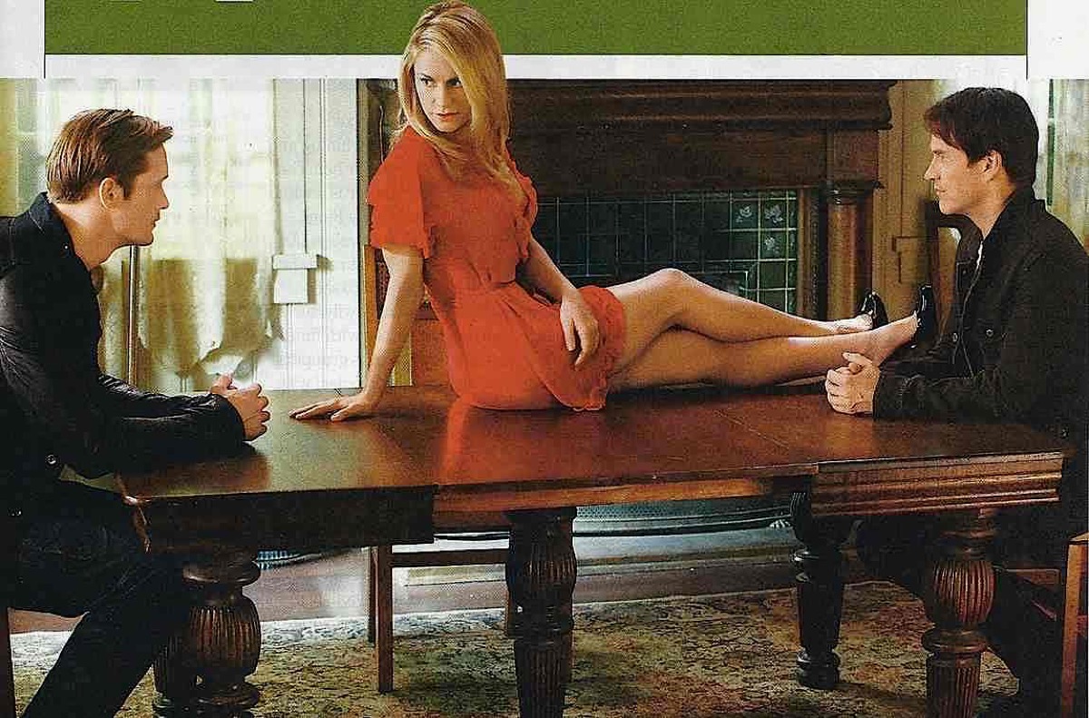 Two vampire men eye a woman in red sitting on a table in "True Blood" 