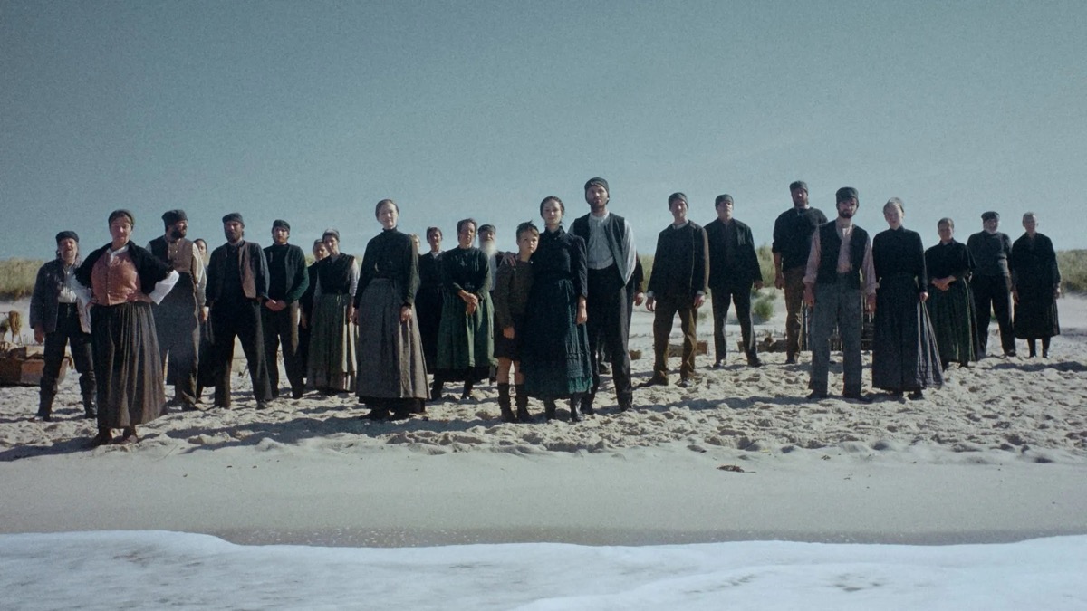 A group of villagers stands on a desolate shore in "Trial of Hein"