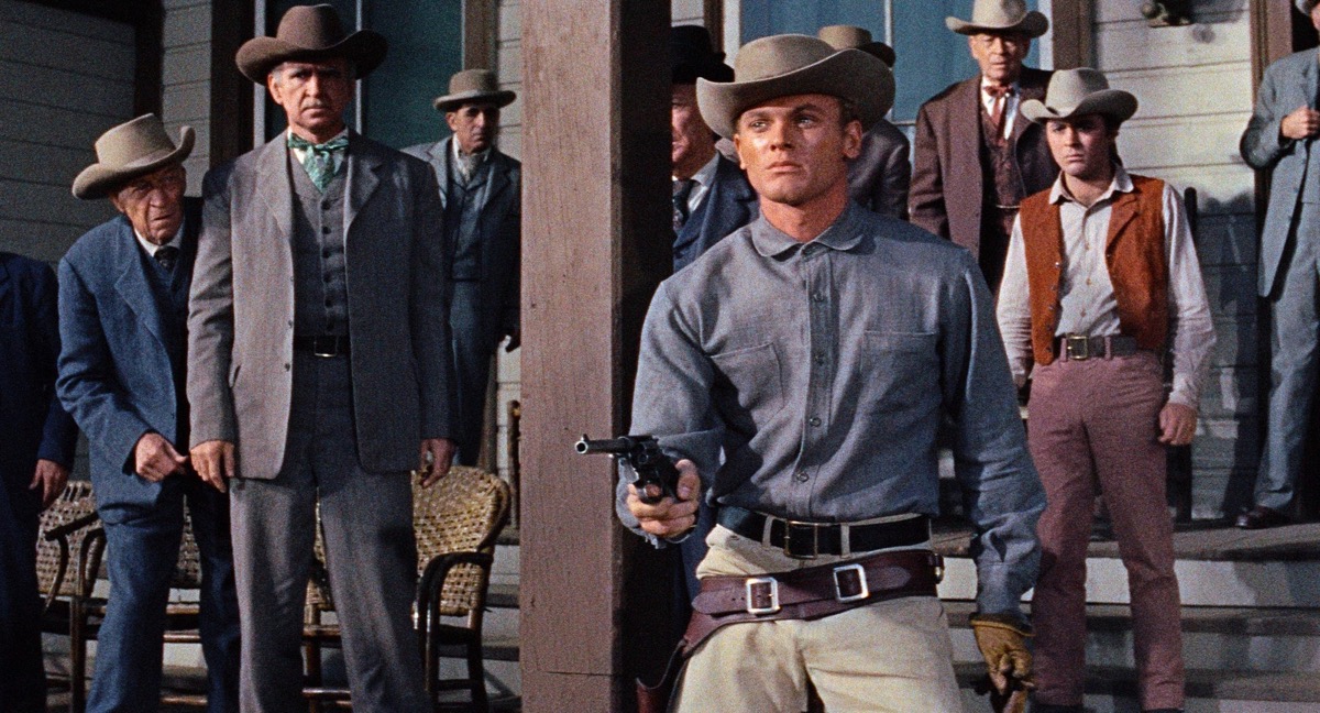 A gunglinger points a pistol in front of a crowd in "Gunman's Walk"