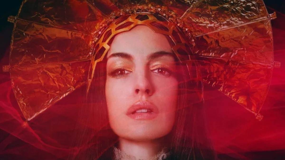 A pop star in a relgious headpiece stands in red light in "Mother Mary"