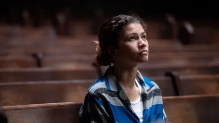 A woman in an auditorium watches the stage in 