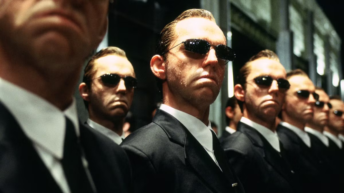 A sunglasses wearing man stands with clones of himself in The Matrix
