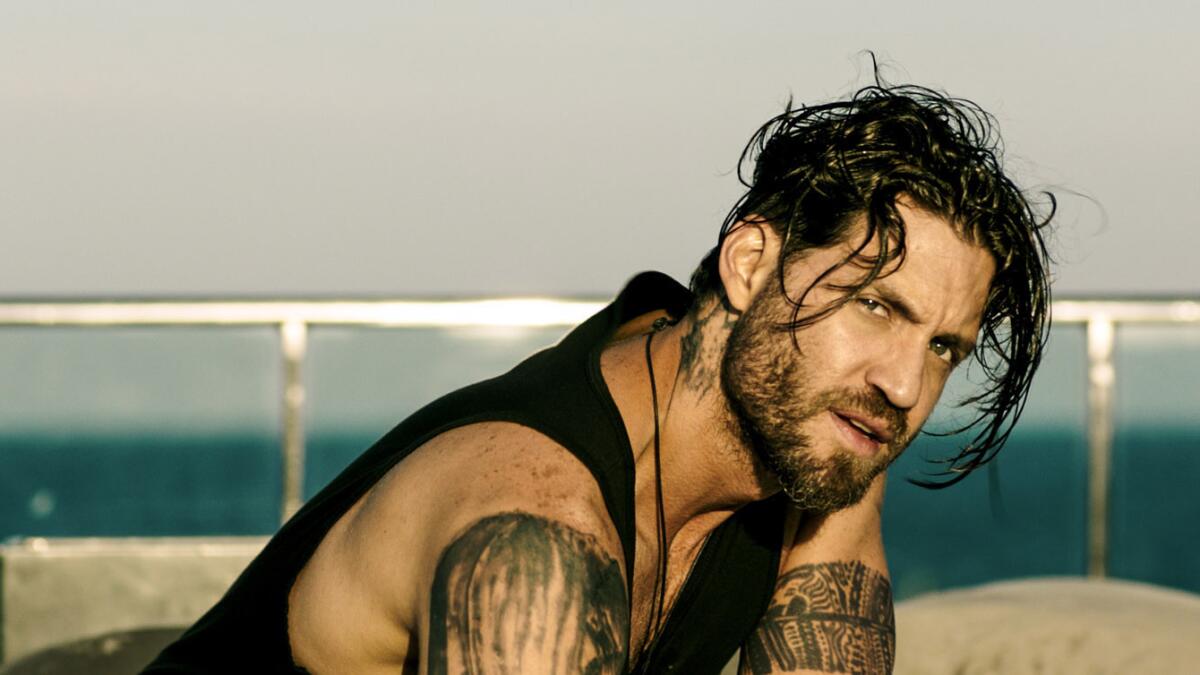 A tattooed man smoulders by the seaside in the Point Break remake