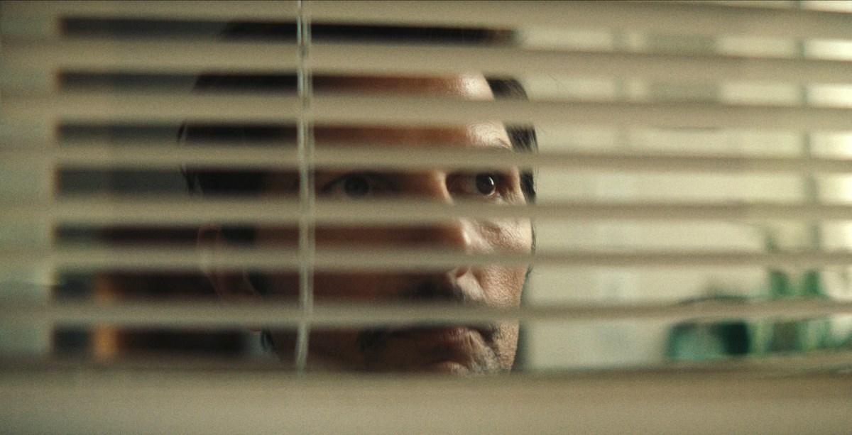 man looking through blinds
