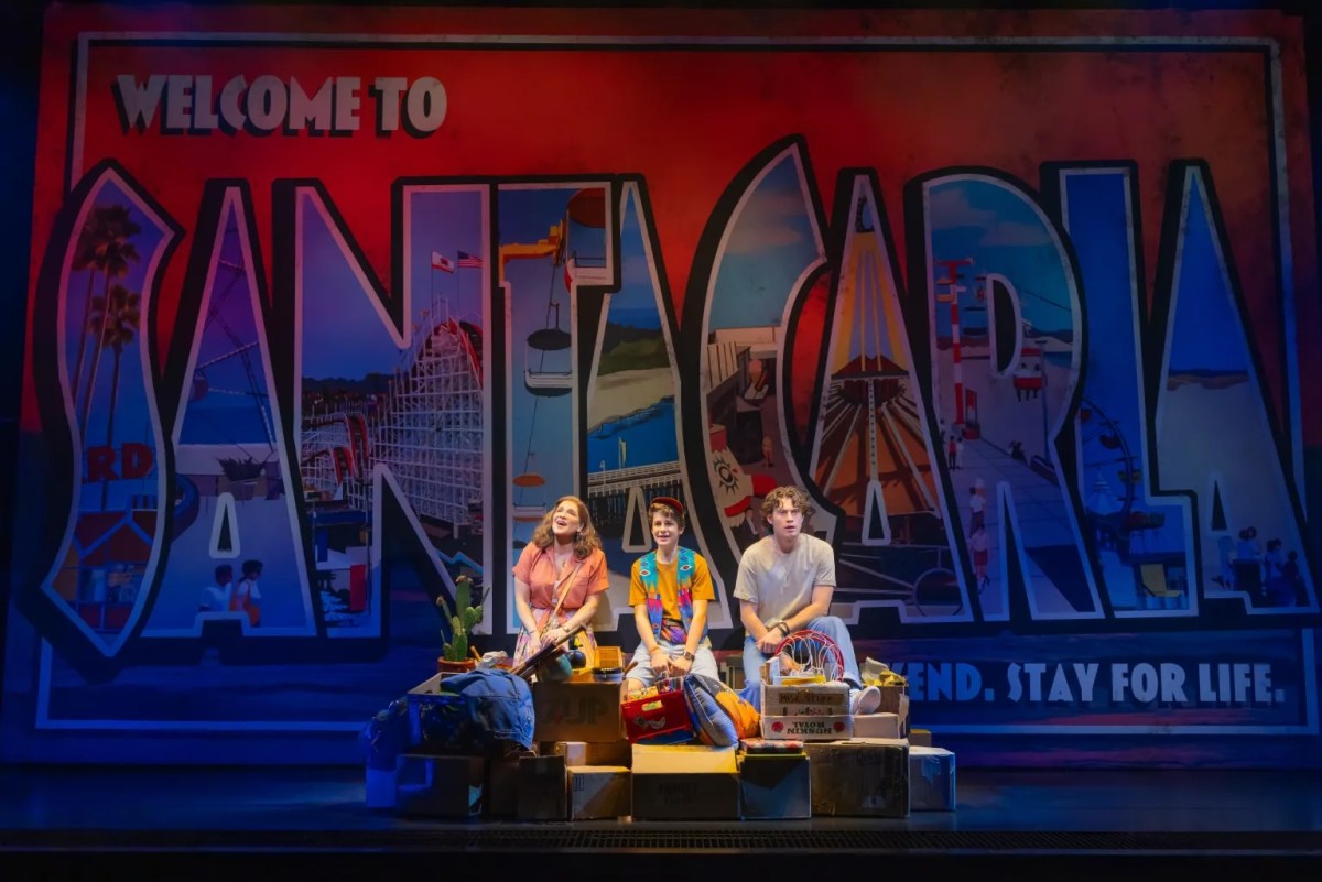 three people sitting in front of a santa carla sign