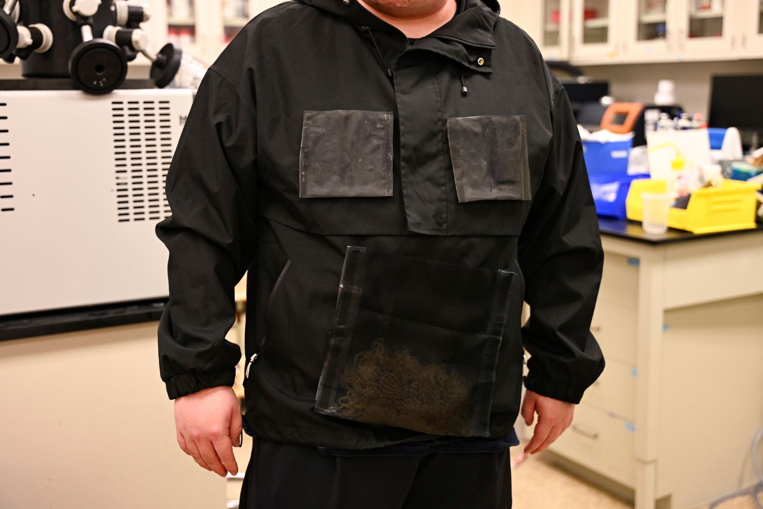 A person is wearing a black jacket with panels; the jacket was created by engineers at The University of Texas at Austin and can harvest water from the atmosphere