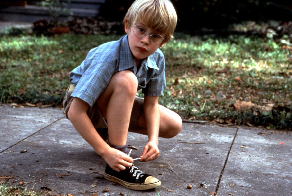 A little boy ties his shoe on the sidewalk in My Girl
