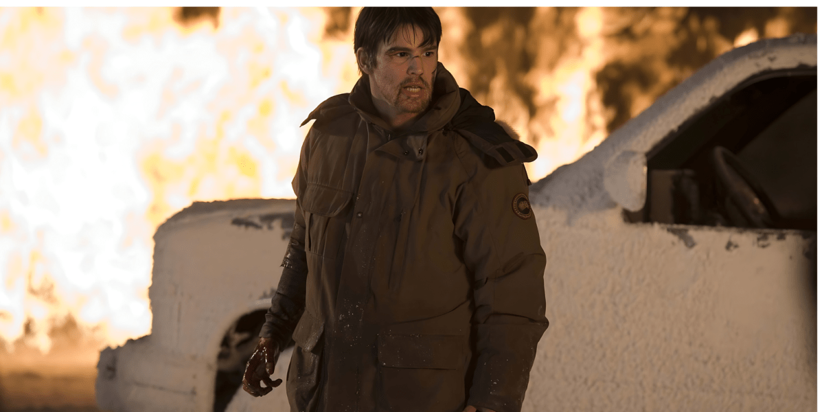 Josh Hartnett, with a bloody hand, stands in front of a snow-covered vehicle; a still from the film 30 Days of Night