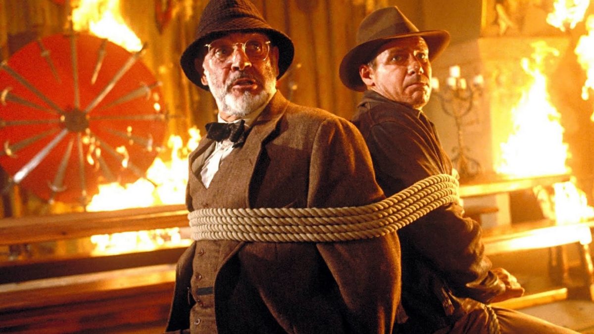 Indiana Jones sits tied up with his father in a burning room in Indiana Jones and the Last Crusade