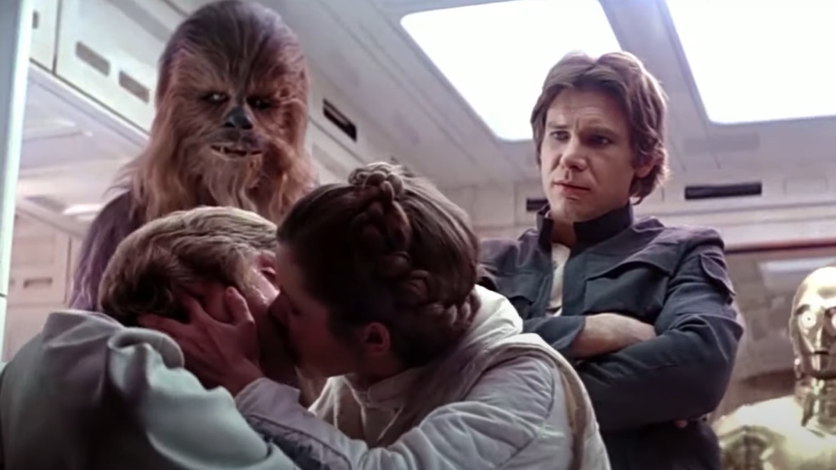 Luke and Leia kiss as Han Solo looks on in Star Wars