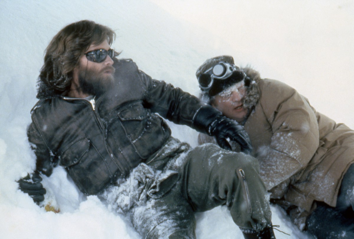 Two men lay on a snow covered ground; a still from the movie The Thing