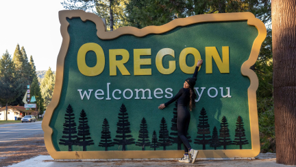 A woman stands in front of a sign reading 