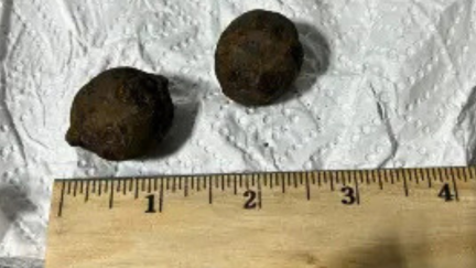 A ruler sits below two small cannonballs