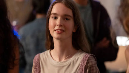 A young girl with brown hair smiling at the camera