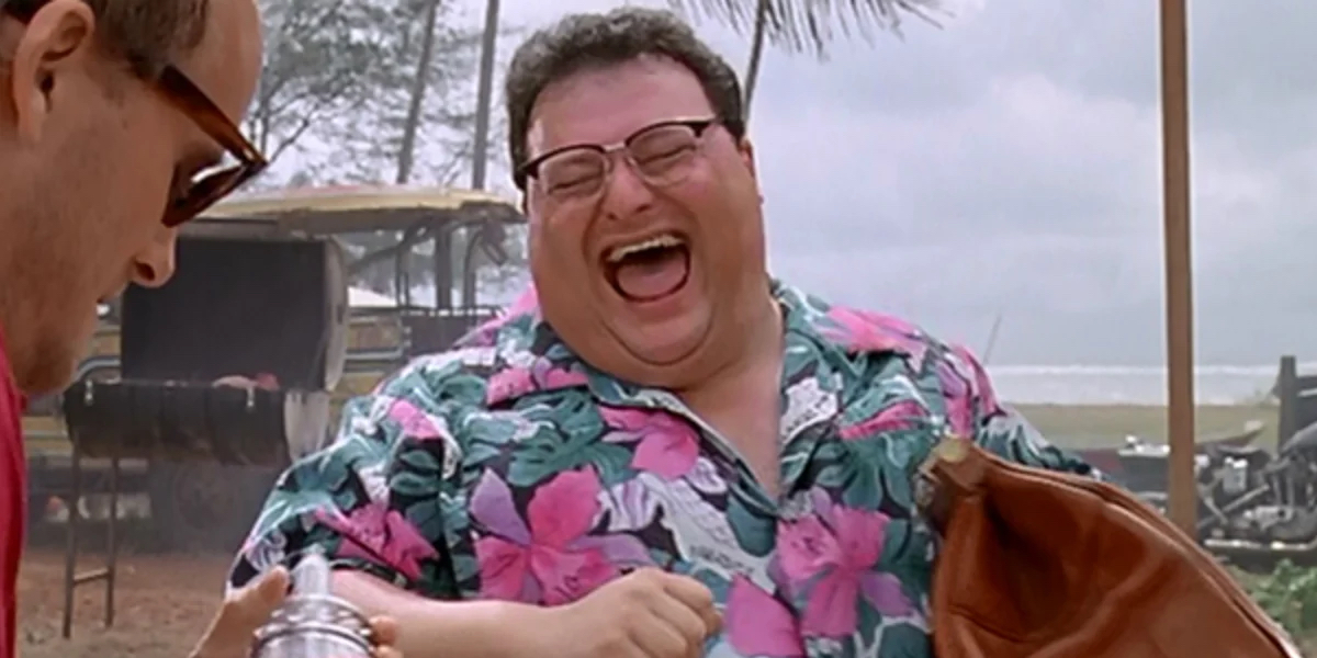 A man in a bright Hawaiian shirt laughing