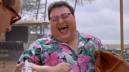 A man in a bright Hawaiian shirt laughing