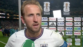 Man by a board at a football match being interviewed