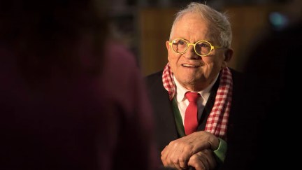 Man wearing glasses with a red tie in a dark room