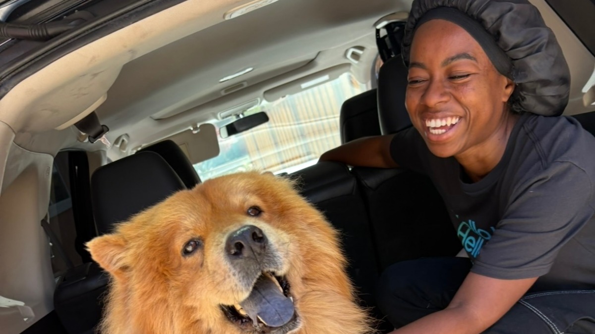 A black woman and a large fluffy dog sit in the back of a hatchback